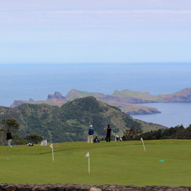 A panoramic view of a coastal golf course with rolling green hills.