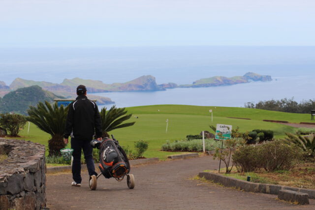 A person walking on a scenic coastal golf course.