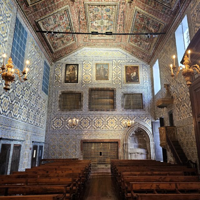 An elegant hall with a richly decorated ceiling and wooden furniture.