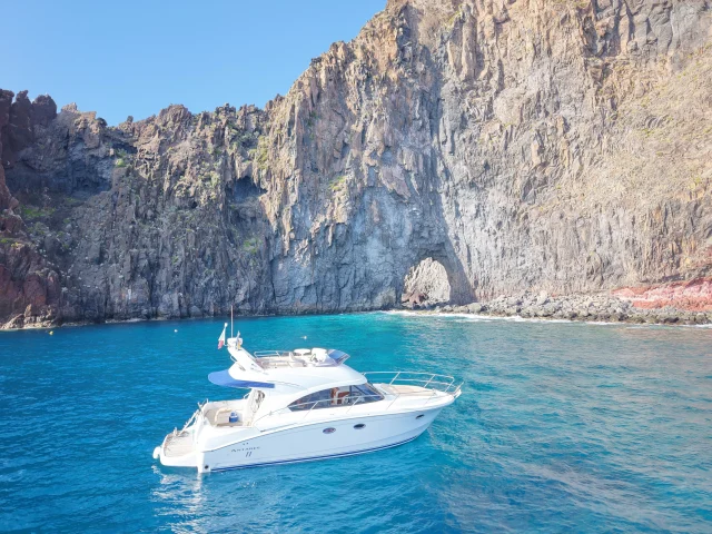 Luxury yacht anchored near dramatic cliffs along the Madeira coastline