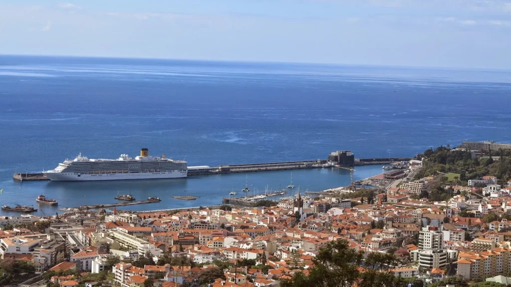 Cruise ship docked at Funchal harbour in Madeira with panoramic view of the city and Atlantic Ocean.